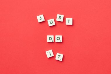 Motivational phrase 'Just Do It' spelled with Scrabble letters on a red background.